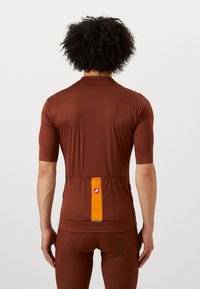Bruine fietsshirt met korte mouwen, gladde stof, achterzak met oranje streep en reflecterend detail. Strak ontwerp met gebogen naden.