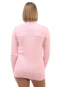Maglione a treccia di colore rosa pallido con orlo e colletto a coste. Presenta un motivo testurizzato con linee verticali e orizzontali sulla schiena.
