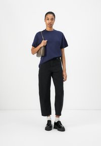Tricou bleumarin din bumbac cu mâneci scurte, asortat cu blugi negri cu talie înaltă, geantă gri și pantofi cu platformă negri.