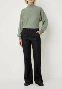 Maglione turtleneck a maglia verde chiaro con maniche larghe, abbinato a jeans neri dritti in denim e calzature nere chunky.