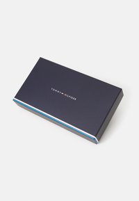 Tommy Hilfiger gave eske i marineblå, rektangulær form med en blank finish. Har et hvitt og rødt aksentstripes langs kanten.