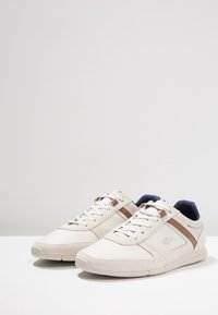 Sneaker beige realizzati in pelle e tessuto, con accenti marroni, un design testurizzato e suole in gomma piatte di colore crema.
