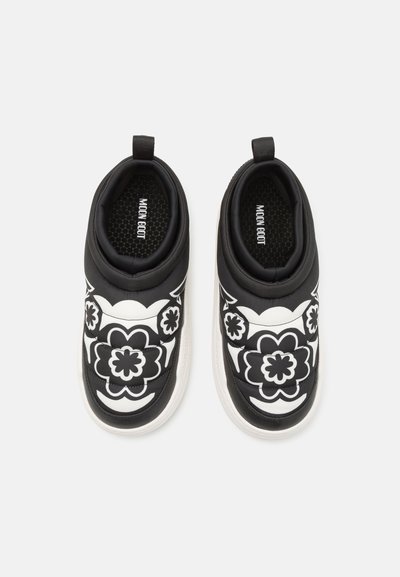 Fekete és fehér slip-on cipők virágmintákkal, párnázott kialakítással, textil felsőrésszel és belső hatszögletű mintázatú gumitalppal.