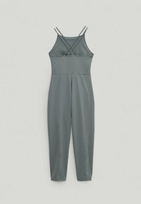 Szary kombinezon z cienkimi ramiączkami i krzyżowanym tyłem. Posiada dopasowaną górę i zwężane nogawki, wykonany z gładkiego, elastycznego materiału.