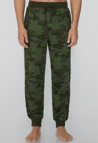 Camo-sweatpants gemaakt van zacht materiaal, in tinten groen en donkerbruin, met een elastische tailleband en een trekkoord, en nauw aansluitende boorden.
