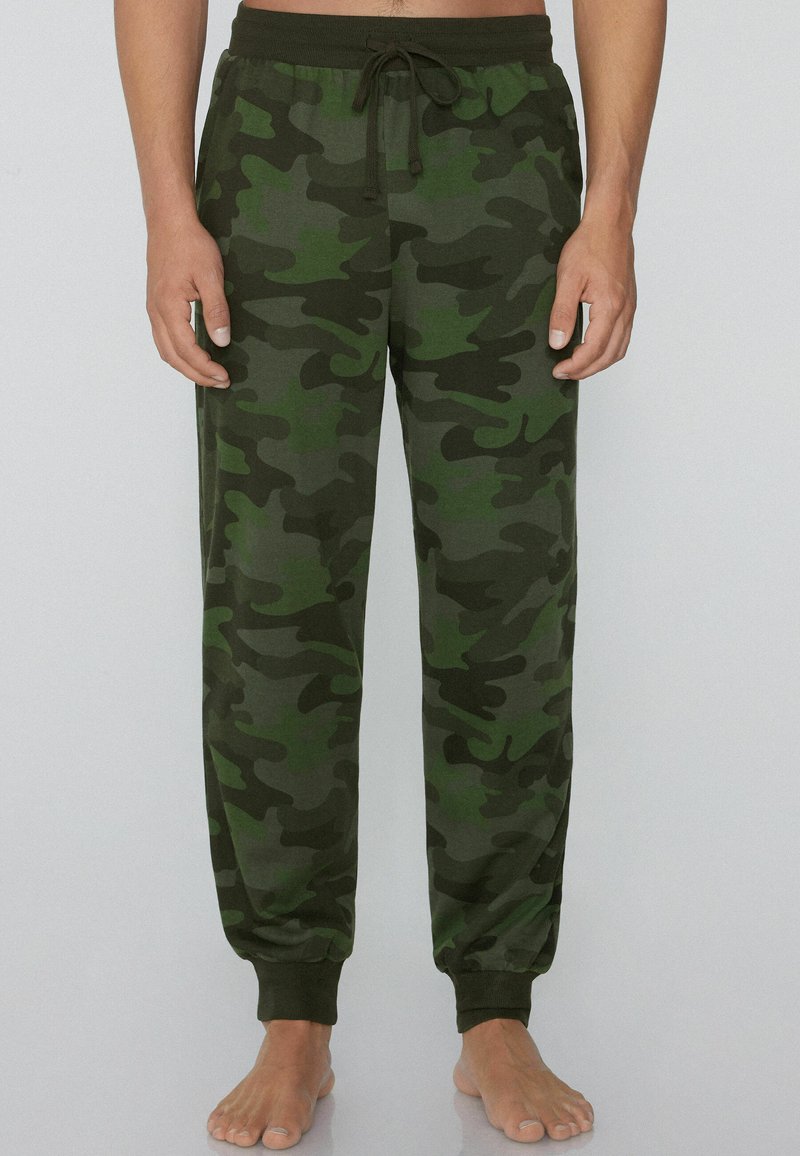 Camo-sweatpants gemaakt van zacht materiaal, in tinten groen en donkerbruin, met een elastische tailleband en een trekkoord, en nauw aansluitende boorden.