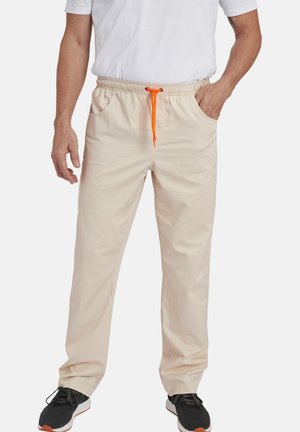 Beige Hose mit elastischem Bund und orangefarbener Kordel, ausgestattet mit zwei seitlichen Taschen; aus leichtem, glattem Stoff hergestellt.