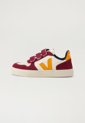 Red and cream velcro sneakers with orange V logo, suede and textile upper, round toe, white sole, and contrasting heel detail.