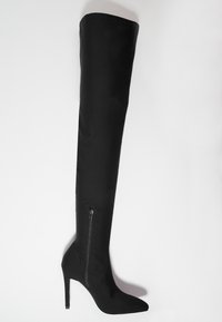 Bota negra por encima de la rodilla con punta afilada, tacón de aguja alto y cremallera lateral. Presenta una textura suave y mate.
