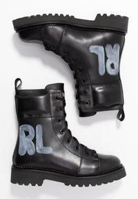 Zwarte leren combat boots met een gestructureerd oppervlak, veters aan de voorkant, een robuuste zool en "RL" in lichtblauw geschilderd aan de zijkant.