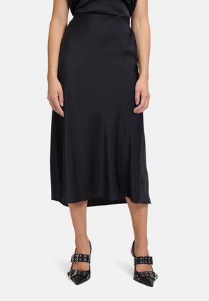 Zwarte satijnen midi-rok met een gladde textuur, met een hoge taille en een licht uitlopende zoom. Gecombineerd met zwarte schoenen met een puntige neus.