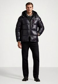 Puffer jacket in shiny black fabric, featuring a zip front, horizontal stitching, and a hood, paired with black pants and shoes.