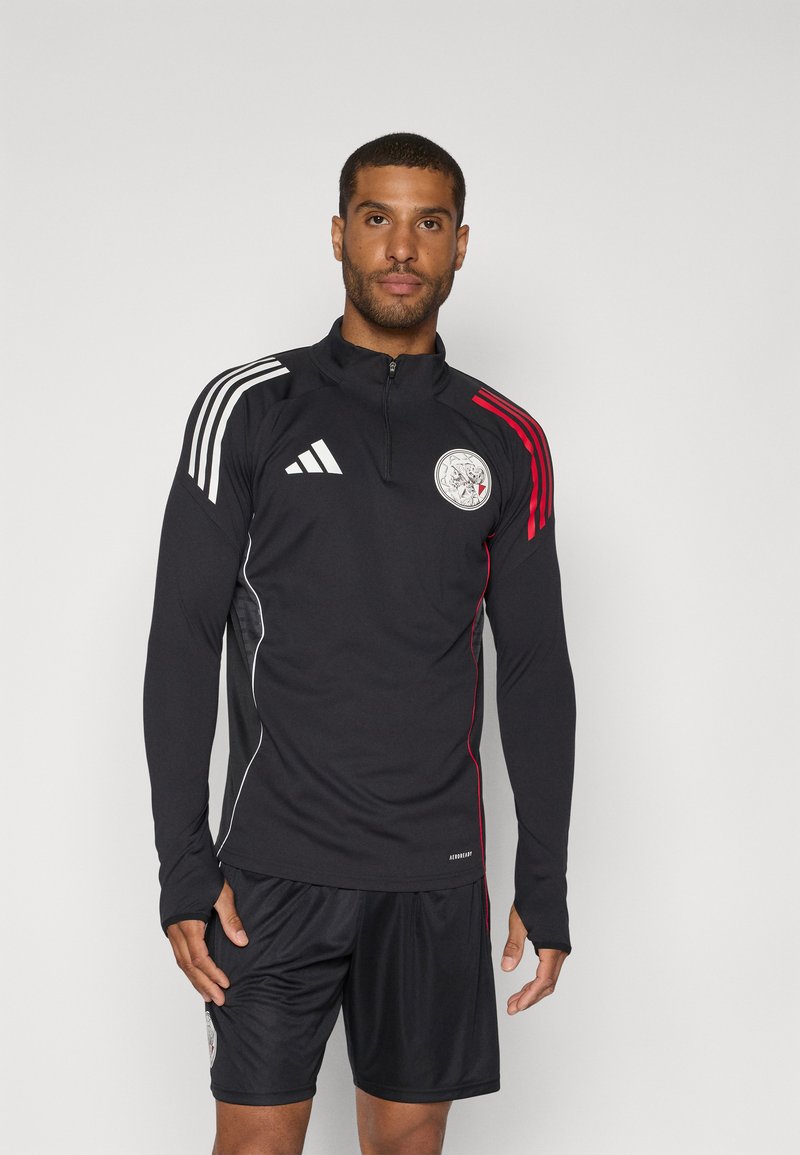 Black athletic top with a quarter zipper, featuring white and red horizontal stripes on the shoulders and a circular logo on the chest.