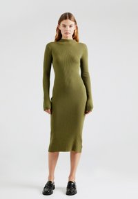 Rippiges, langärmliges Kleid aus olivgrünem Stoff, figurbetonte Silhouette, Rundhalsausschnitt, mit Midi-Länge und Schlitz am Saum.