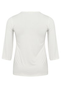 Witte lange mouwen top met een ronde halslijn, zachte textuur en iets getailleerde pasvorm. Naadloze schouders en taps toelopende mouwen.