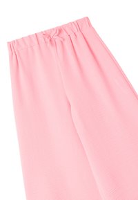 Pantaloni della tuta rosa chiaro realizzati in tessuto morbido con cintura elastica, dotati di cordoncino e vestibilità comoda. Superficie liscia e texturizzata.