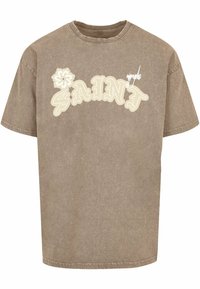 Khaki oversize tričko s krátkymi rukávmi. Obsahuje krémový potlač "SAINT" a grafiku kvetu. Vyrobené z jemného, textúrovaného bavlneného materiálu.
