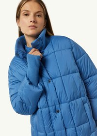Padded jacket w jaskrawym niebieskim kolorze z wysokim kołnierzem, prążkowanymi mankietami i zapięciem na zatrzaski. Posiada pikowaną teksturę.
