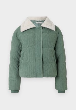 Chaqueta acolchada de pana verde con un cuello mullido de color crema, cierre frontal y dos bolsillos laterales. Textura acanalada en toda la prenda.