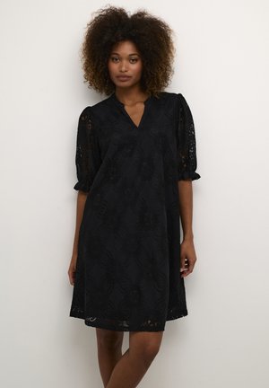 Black dress featuring floral lace pattern, V-neckline, and puff sleeves. Soft texture with a flared silhouette and scalloped hem.