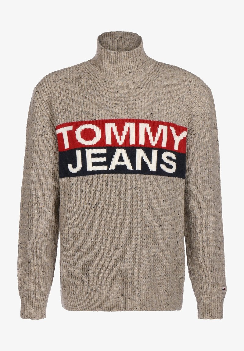 Beige svetr s ribovanou texturou, vysokým límcem a odvážným pruhovaným designem se slovy "TOMMY" v červené a "JEANS" v bílé a námořnické modři.