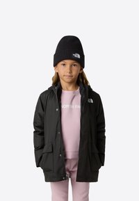 Černá voděodolná bunda s kapucí, přední zip, boční kapsy, přes světle růžovou mikinu. Černá pletená čepice s logem.