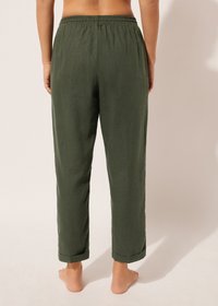 Pantalons en lin vert olive, ample, avec une taille élastique et des poignets retroussés. Texture lisse avec un design décontracté, vu de dos.