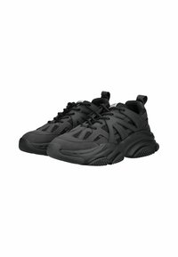 Zapatillas deportivas negras hechas de malla y material sintético, con una suela gruesa, diseño con cordones y patrones de recortes únicos.