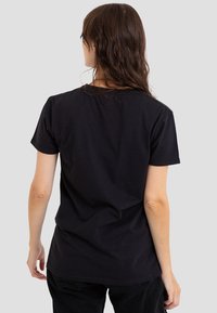Black cotton t-shirt with short sleeves, rounded neckline, and a relaxed fit. Smooth texture, minimal design, no visible patterns or accents.