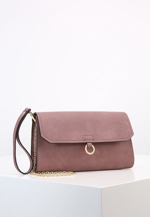 Støvet lyserød faux suédetaske med klaplukning, guldhardware og en aftagelig kædetras. Har et cirkulært accent på fronten.