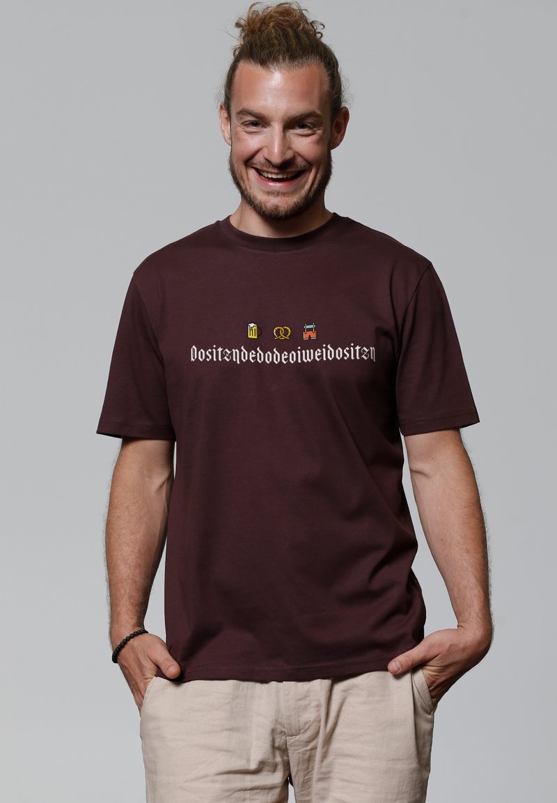 T-shirt à manches courtes bordeaux en coton, orné d'images et de texte décoratifs dans une couleur contrastante sur le devant.