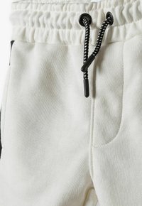 Witte sweatpants met een elastische tailleband en een zwarte trekkoord, zijzakken en een zachte, gestructureerde stof.