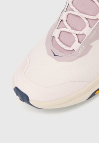 Αθλητικό παπούτσι σε ανοιχτό ροζ χρώ μα με υφή στην επιφάνεια, στρογγυλή μύτη και σύστημα κορδονιών σε λιλά απόχρωση. Διαθέτει ανθεκτική σόλα με ναυτικές αποχρώσεις.