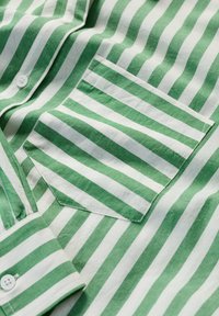 Camicia a righe verdi e bianche realizzata in tessuto leggero, con taschino sul petto e dettagli dei polsini con bottoni.