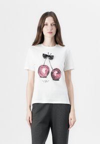 Hvid bomulds T-shirt med et grafisk motiv af to lyserøde kirsebær med sorte kanter og en lille sort sløjfe over, paired med mørkegrå bukser.
