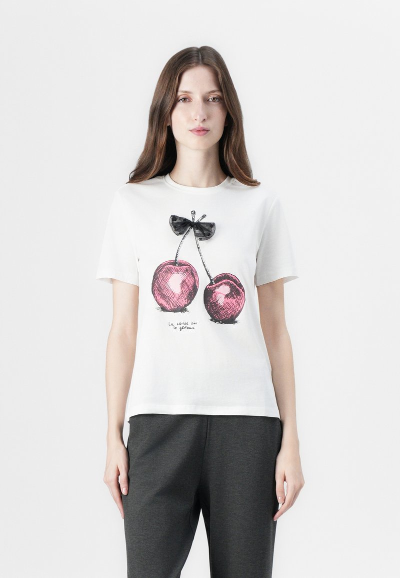 Hvid bomulds T-shirt med et grafisk motiv af to lyserøde kirsebær med sorte kanter og en lille sort sløjfe over, paired med mørkegrå bukser.