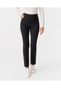 Zwarte op maat gemaakte broeken van rekbaar materiaal, met een gladde textuur en een slim fit, gecombineerd met witte sneakers.