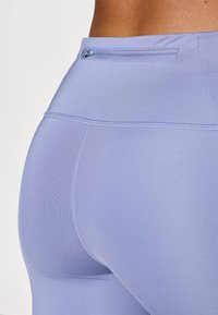 Lyse lilla leggings lavet af glat, strækbart stof. Har en lille lynlåslomme i taljen og flade sømme for et elegant udseende.