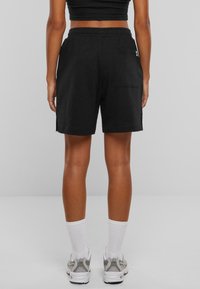 Shorts negri din bumbac cu un brâu elastic, buzunare laterale și un buzunar pe spate. Croială dreaptă cu o ajustare ușor lejeră.