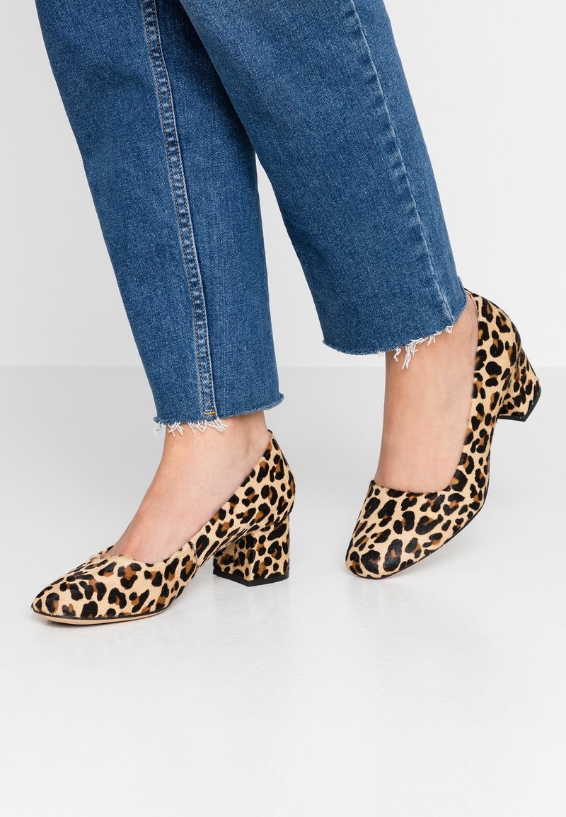 Chaussures à talons imprimées léopard avec un bout pointu, fabriquées en tissu doux, avec un talon épais et une silhouette élégante, portées avec un jean effiloché.