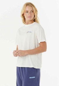 Weißes T-Shirt mit kurzen Ärmeln und rundem Halsausschnitt sowie einem bunten "Rip Curl"-Logo auf der Brust. Einfaches Design und lockere Passform.