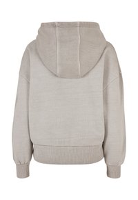 Felpa corta grigia chiara con un ampio cappuccio, polsini a coste e un tessuto morbido e testurizzato. Design semplice e minimalista senza loghi visibili.