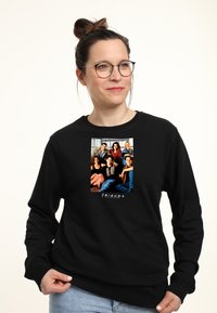 Felpa nera con un grafico centrale di sei persone, con la scritta "FRIENDS" in basso, che evidenzia un tessuto morbido e casual.