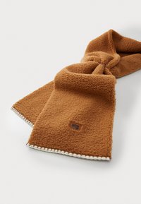Écharpe en polaire beige avec une surface texturée, dotée d'un bord surpiqué et d'un petit patch de marque. Plusieurs plis créent un design décontracté.