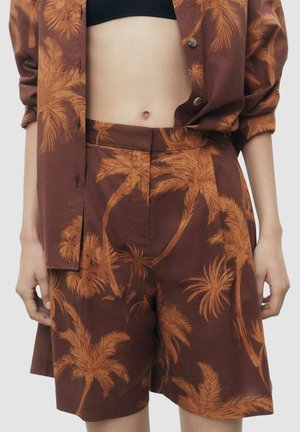 Pantaloni corti marroni e camicia abbinata con un motivo di palme nei toni dell'arancione, realizzati in tessuto leggero con una vestibilità comoda.