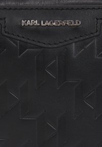 Portafoglio in pelle nera con un motivo geometrico in rilievo, un bordo cucito e una placca con logo metallico recante la scritta "KARL LAGERFELD."