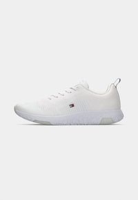 Weiße Sneaker mit einem strukturierten Strickobermaterial, flachen Schnürsenkeln und einer Gummisohle mit einem gemusterten Profil. Mit einem kleinen Logodetail an der Seite.
