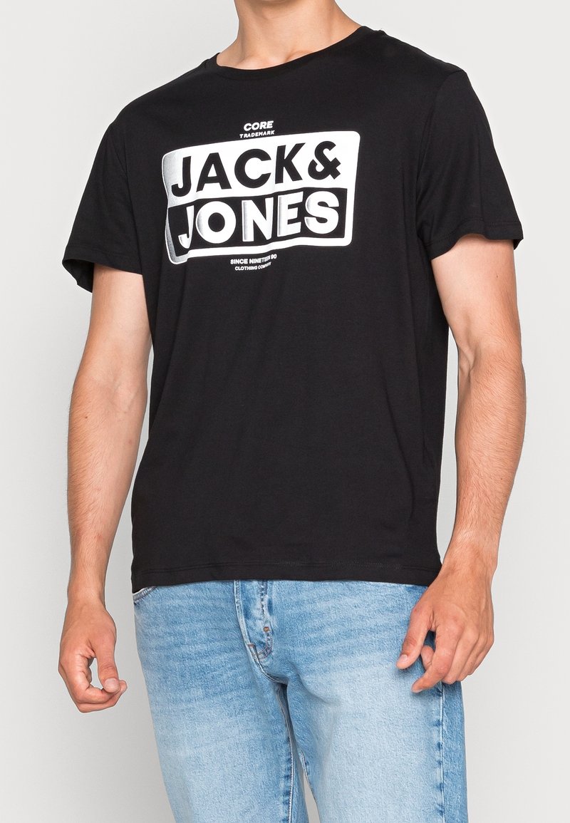 Černé bavlněné tričko s velkým bílým potiskem "JACK & JONES" na hrudi, s kulatým výstřihem a krátkými rukávy.