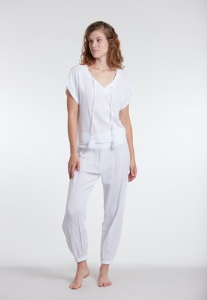 Completo bianco, leggero e texturizzato con una maglietta a maniche corte con scollatura a V e cordoncino, abbinato a pantaloni tapered con vita elastica.