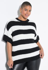 Stribet strikket sweater i sort og hvid med korte ærmer, rund halsudskæring og ribbet kant, parret med sorte bukser i faux læder.